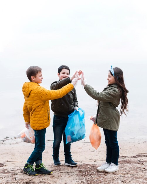 Volledig schot van kinderen met plastic zakken