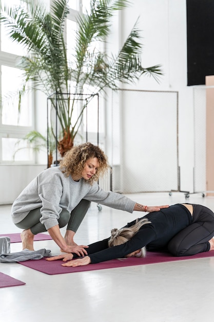 Gratis foto volledig schot vrouw die zich uitstrekt op de mat