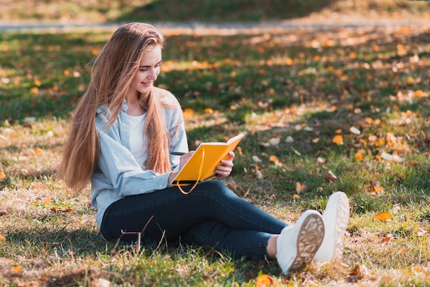 Gratis foto volledige geschotene blondevrouw die in een notitieboekje schrijven