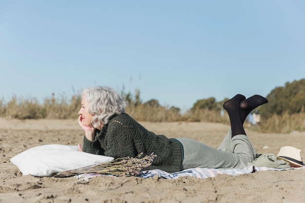 Gratis foto volledige geschotene vrouw die op het strand legt