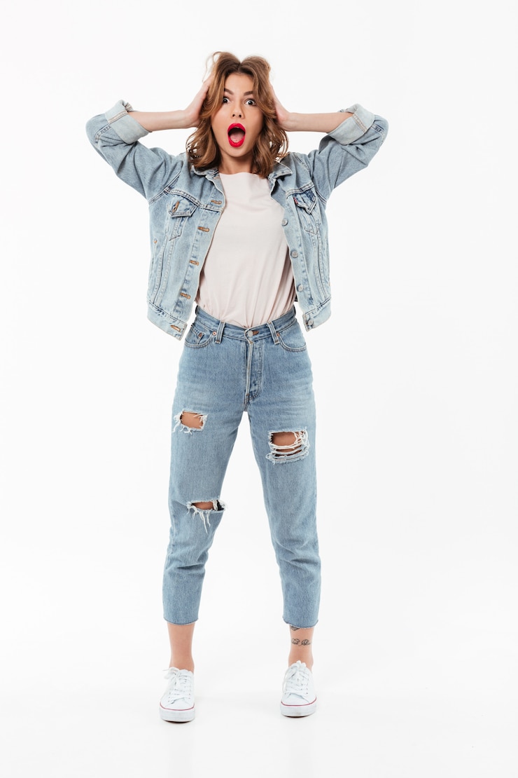 Gratis Foto volledige lengte geschokte vrouw die in denimkleren haar hoofd over witte muur houdt