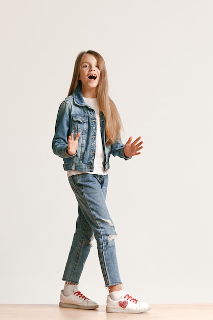 Volledige lengte portret van schattige kleine tiener in stijlvolle jeans kleding camera kijken en glimlachen