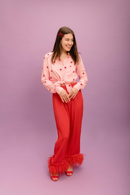 Volledige lengte schattige jonge blanke brunette in blouse broek en schoenen kijkt weg op paarse achtergrond Mensen oprechte emoties levensstijl concept