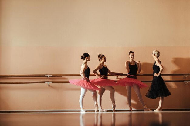 Volledige lengte van balletinstructeur en ballerina's die praten tijdens een les op balletschool Ruimte kopiëren