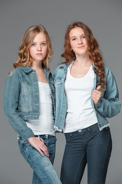 Volledige lengte van jonge slanke vrouwelijke meisje in denim jeans op grijs