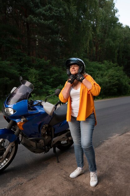 Gratis foto volledige opname coole oude vrouw met motorfiets