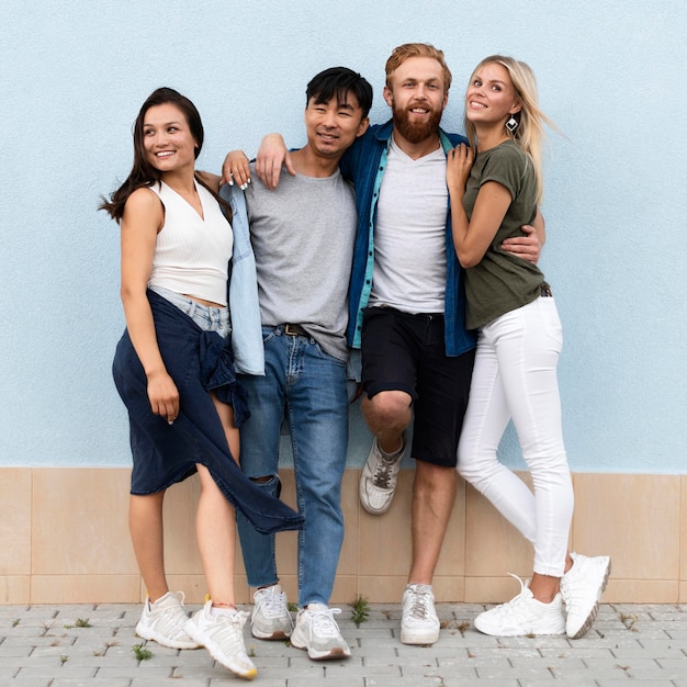 Gratis foto volledige schot vrienden poseren in de buurt van muur