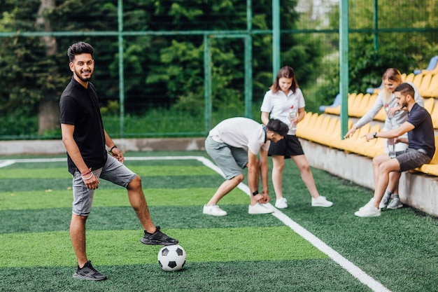 Volledige weergave van atletische Afro-Amerikaanse voetballer die met bal op groen veld blijft