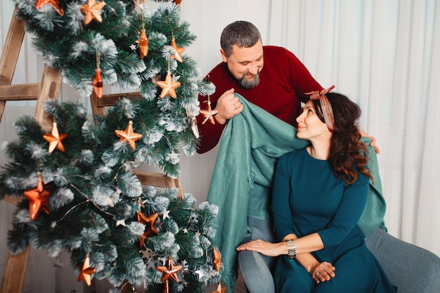 Volwassen familie om thuis te zitten in de buurt van de kerstboom