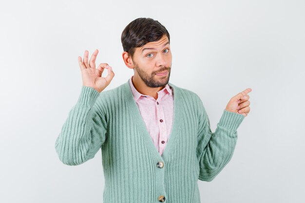 Volwassen man die een goed gebaar toont, naar rechts wijst in shirt, vest en er zelfverzekerd uitziet, vooraanzicht.