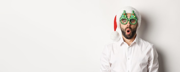 Volwassen man die wintervakantie viert met een kerstfeestbril en een kerstmuts die er verrassend uitziet