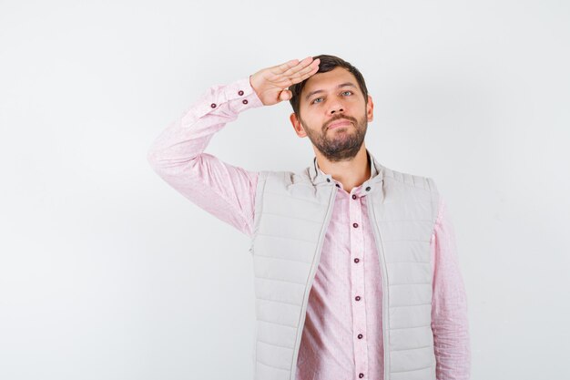 Volwassen man in shirt, mouwloos jasje met saluutgebaar en zalig, vooraanzicht.