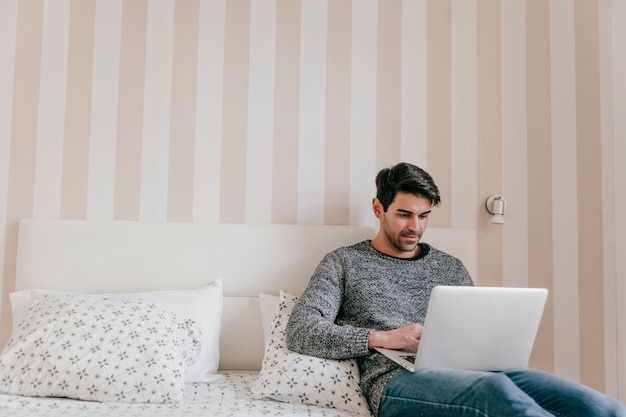 Volwassen man met laptop op bed