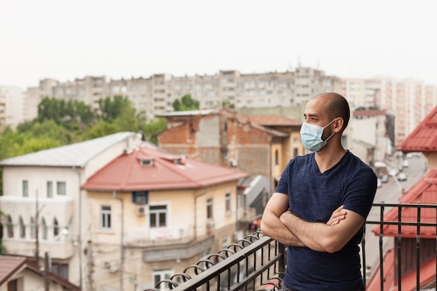 Volwassen man op balkon met gezichtsmasker tijdens wereldwijde pandemie.