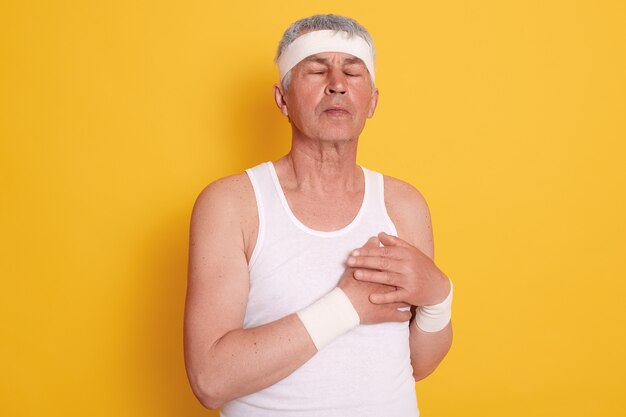 Volwassen man poseren met gesloten ogen en het aanraken van zijn borst, voelt pijn in het hart, heeft behandeling nodig, heeft een hartaanval na het sporten