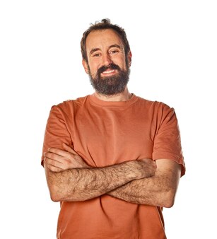 Volwassen man van in de 40 met baard die naar camera kijkt en armen kruist met vriendelijke en zelfverzekerde uitdrukking witte geïsoleerde achtergrond voor knipsel