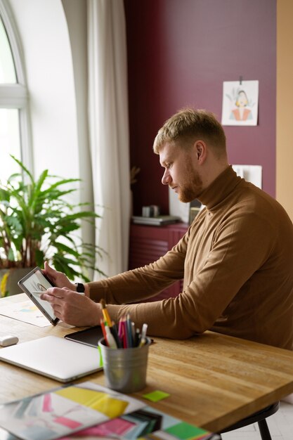 Volwassen mannelijke illustrator die aan tabletapparaat werkt