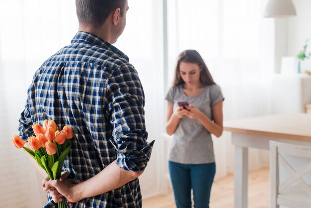 Volwassen mannetje die verrassing voor vrouw met telefoon voorbereiden