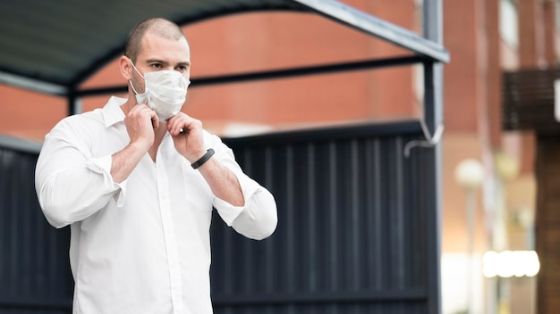 Volwassen mannetje met chirurgisch masker dat op de bus wacht