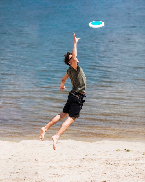 Gratis foto volwassen mens die voor het vangen van frisbeeschijf springt