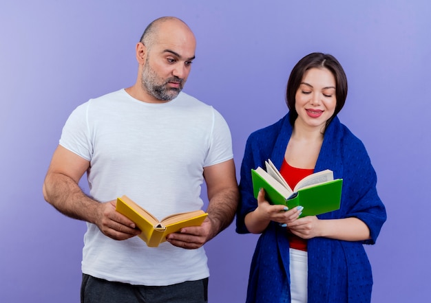 Volwassen paar tevreden vrouw verpakt in sjaal boek lezen onder de indruk man met boek en kijken naar haar boek