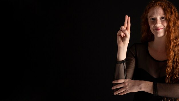 Volwassen vrouw die gebarentaal met exemplaarruimte onderwijst