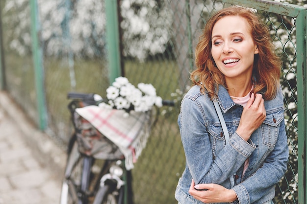 Gratis foto volwassen vrouw die naast lentebloemen staat