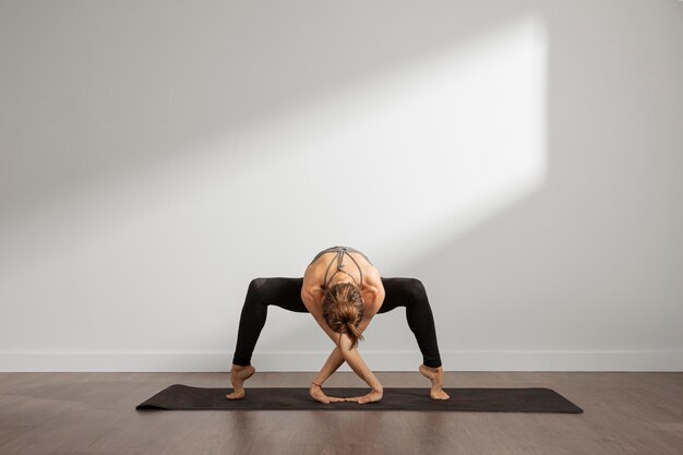 Volwassen vrouw die thuis yoga beoefent