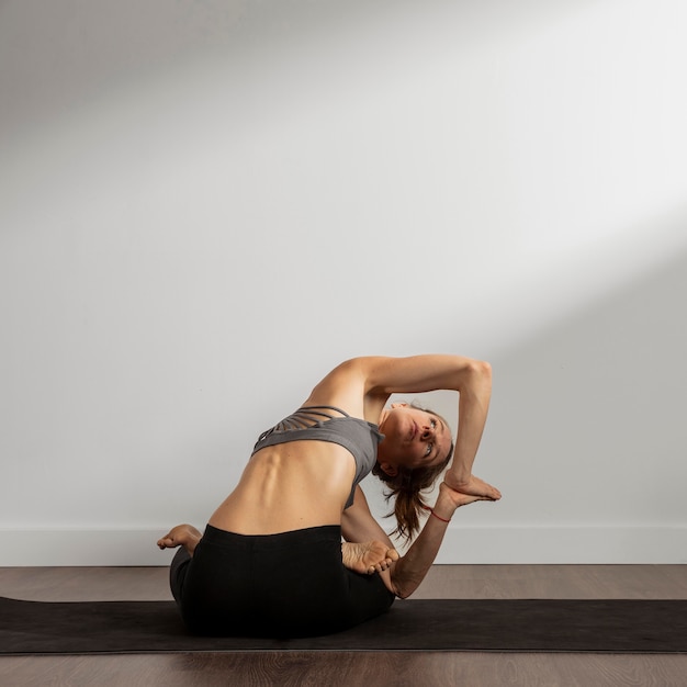 Volwassen vrouw die thuis yoga beoefent