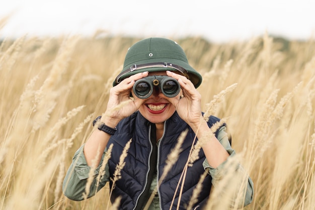 Gratis foto volwassen vrouw die verrekijkers onderzoekt