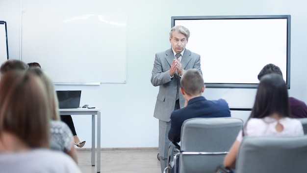 Volwassen zakenman maakt een rapport voor werknemers tijdens een vergadering op kantoor.