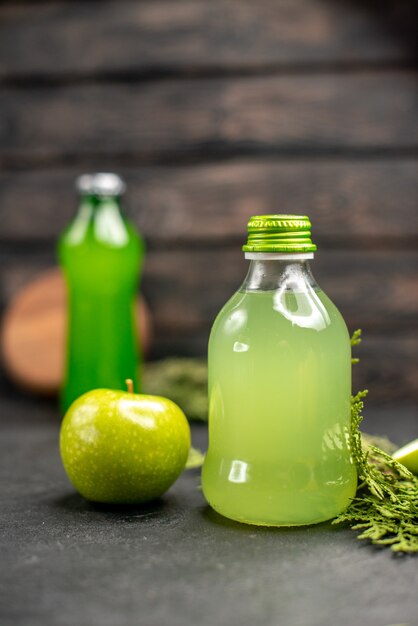 Vooraanzicht appelsap in fles appel gesneden appels groene fles op houten oppervlak