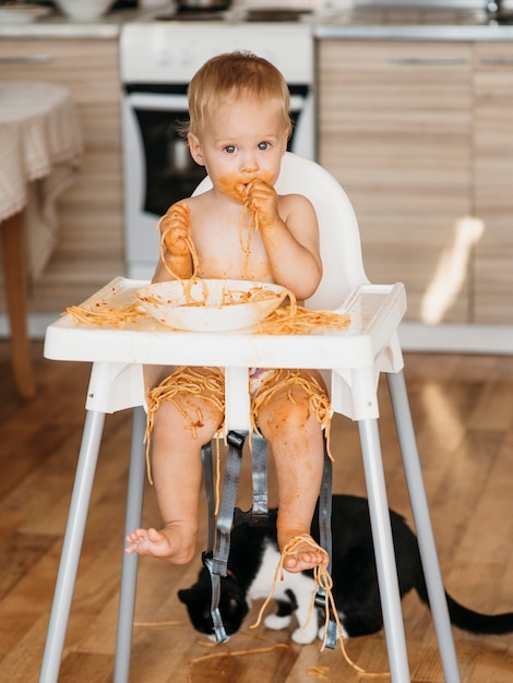 Vooraanzicht babyjongen die een puinhoop met pasta maakt