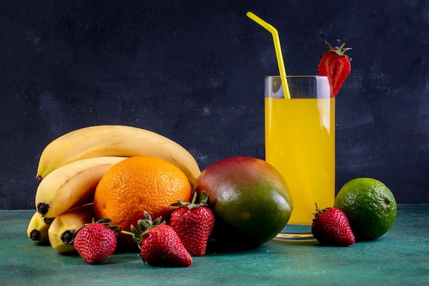 Vooraanzicht bananen met mango oranje aardbeien limoen en een glas sinaasappelsap