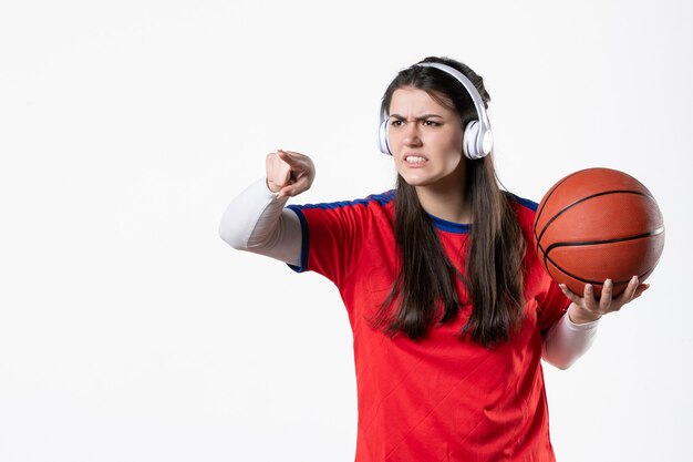 Vooraanzicht boos jong wijfje in sportkleren met basketbal