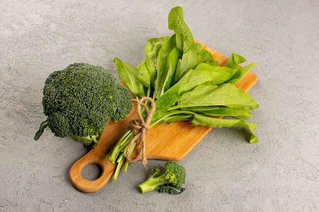 vooraanzicht broccoli groen vers samen met bladeren op het bruine houten bureau op de grijze vloer