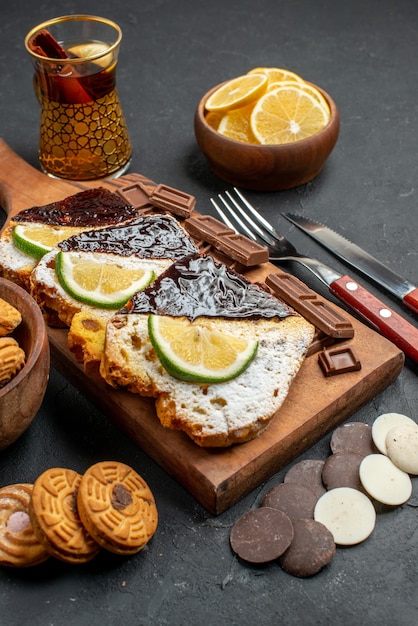 Vooraanzicht cakeplakken met chocolade en koekjes op donkere achtergrond