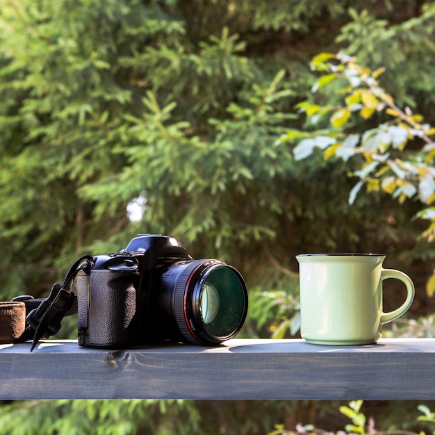 Vooraanzicht camera anc kopje koffie in de natuur