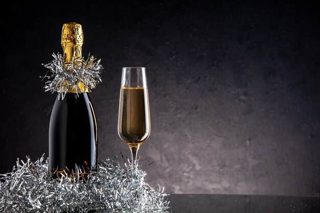 Vooraanzicht champagne in fles en glas op donkere ondergrond