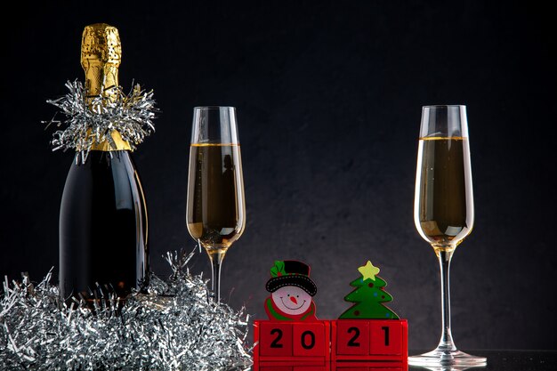 Vooraanzicht champagne in fles en glazen houtblokken op donkere ondergrond