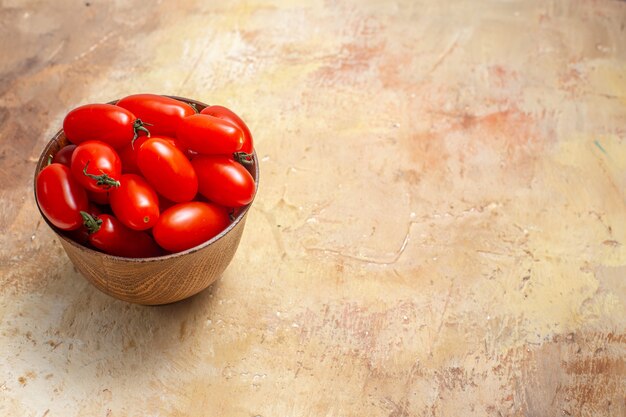 Vooraanzicht cherrytomaatjes in houten kom op amberkleurige vrije ruimte