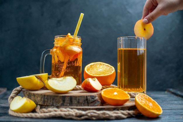 Vooraanzicht cocktail gesneden sinaasappelen en appels op een houten bord op donkere geïsoleerde achtergrond