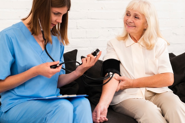 Vooraanzicht dat de bloeddruk van de oude vrouw controleert