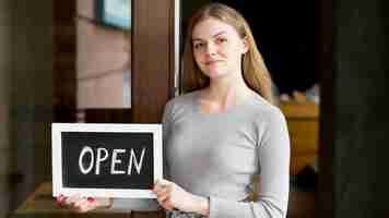 Gratis foto vooraanzicht dat van vrouw open teken voor koffiewinkel houdt