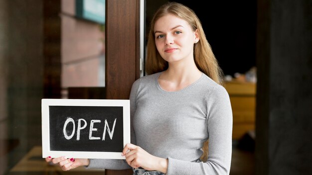 Vooraanzicht dat van vrouw open teken voor koffiewinkel houdt