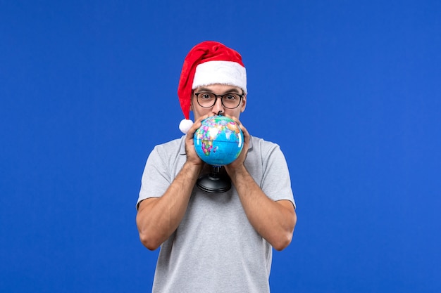 Vooraanzicht de jonge mannelijke wereldbol van de holdingsaarde op het blauwe mannetje van de de vakantiereis van het muurvliegtuig