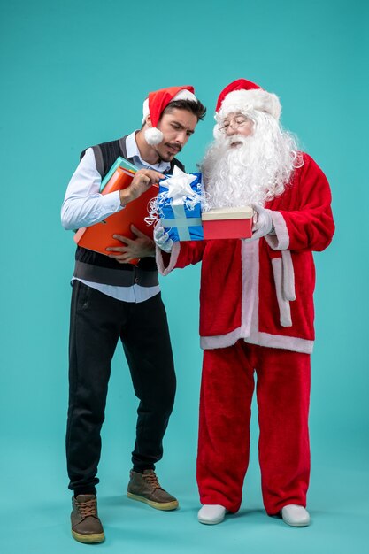 Vooraanzicht de Kerstman met jong mannetje en stelt op blauw bureau voor