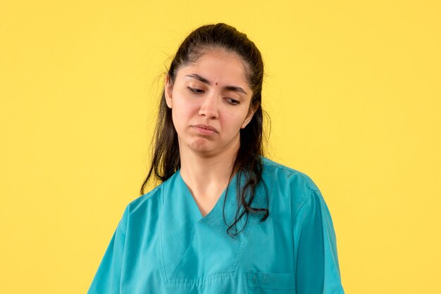 Vooraanzicht depressieve vrouwelijke arts die zich op gele achtergrond bevindt