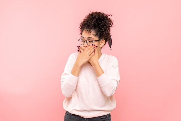 Vooraanzicht die van jonge vrouw haar mond op roze muur behandelen