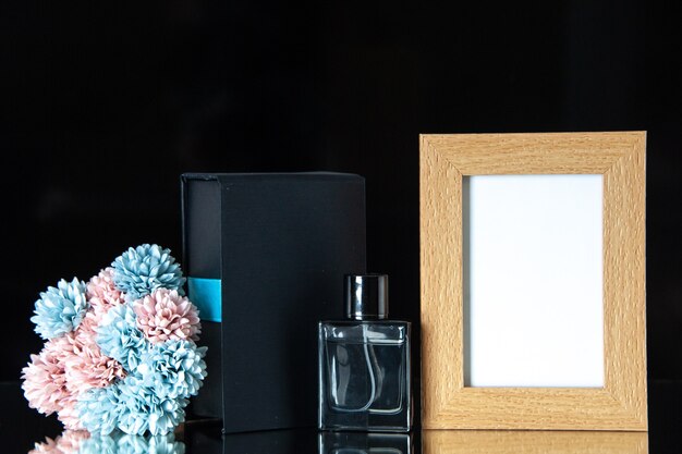 Vooraanzicht dure parfum met bloemen en fotolijst op een zwarte tafel